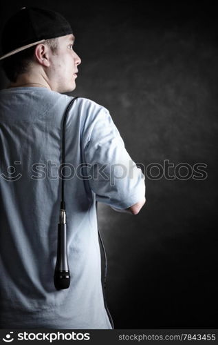 Rapper attitude rap singer hip Hop Dancer performing. Young man with cap microphone back view black grunge background