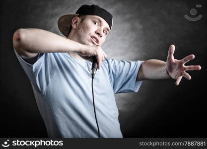 Rapper attitude rap singer hip Hop Dancer performing. Young man with microphone singing hand cool gesture black grunge background