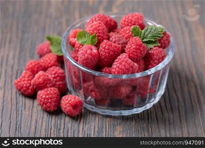 Raspberries in a bowl on a wooden background. Raspberries in a bowl
