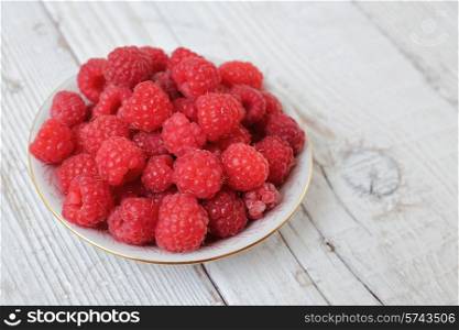 Raspberries in a bowl on a wooden table