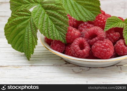 Raspberries in a bowl on a wooden white table