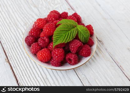 Raspberries in a bowl on a wooden white table