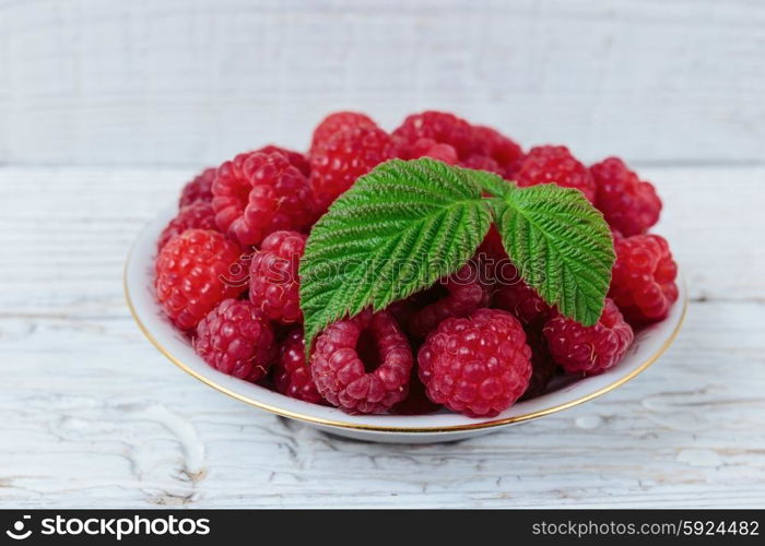 Raspberries in a bowl on a wooden white table