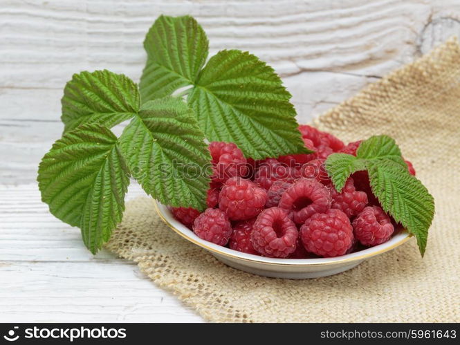 Raspberries in a bowl on a wooden white table