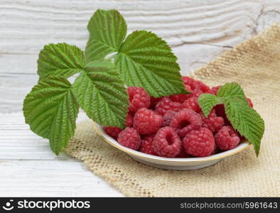 Raspberries in a bowl on a wooden white table