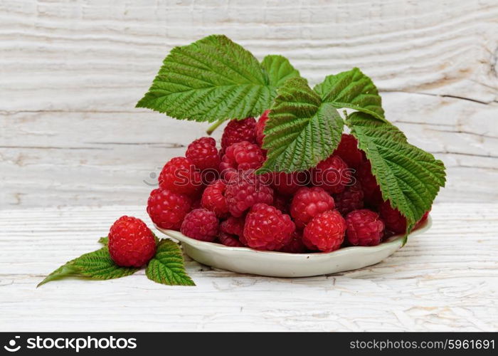 Raspberries in a bowl on a wooden white table