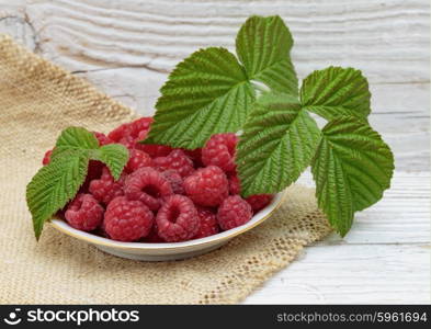 Raspberries in a bowl on a wooden white table