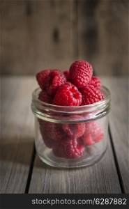 Raspberries in rustic setting with wooden background