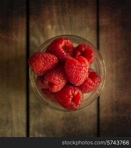 Raspberries in rustic setting with wooden background with added texture filter