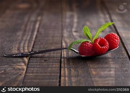 Raspberries on old spoon and mint on grunge wooden board. Natural healthy food. Still life photography