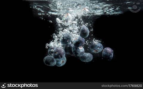 Raspberries splashing in water on black background. Blueberries splashing in water on black