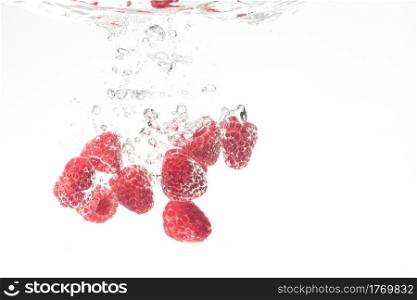 Raspberries splashing in water on white background. Raspberries splashing in water on white