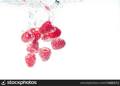 Raspberries splashing into crystal clear water with air bubbles. Isolated fruits on white background. Raspberries splashing into crystal clear water with air bubbles