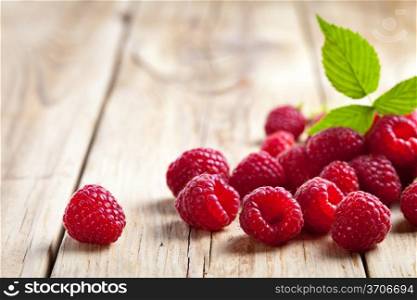 Raspberries with leaf on wooden table background. Copy space