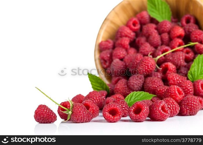 Raspberries with leaves in wooden bowl on white background