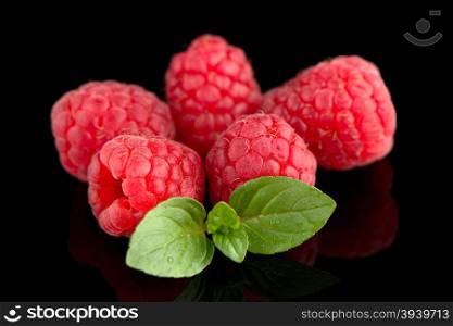 Raspberries with leaves isolated on black background background