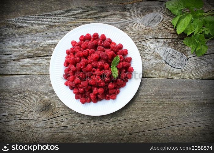 Raspberry fruits in plate on old cutting board, healthy pile of summer berries on grey wooden background, . selective focus .. Raspberry fruits in plate on old cutting board, healthy pile of summer berries on grey wooden background, . selective focus