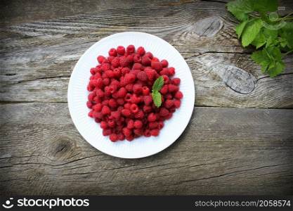 Raspberry fruits in plate on old cutting board, healthy pile of summer berries on grey wooden background, . selective focus .. Raspberry fruits in plate on old cutting board, healthy pile of summer berries on grey wooden background, . selective focus
