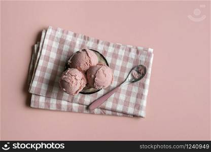 Raspberry ice cream in a glass bowl on napkin, on pink seamless background. Above view of berries ice cream. Homemade red ice cream. Summer dessert.