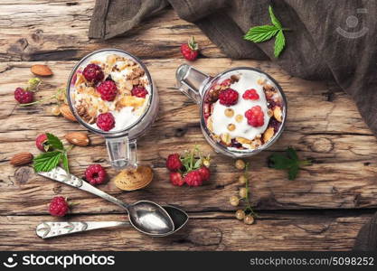 Raspberry ice cream in mug. Raspberry ice cream with almonds and currants in glass cup.Sundae on a vintage rustic background.