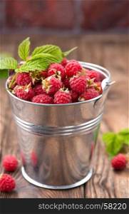 raspberry in metal bowl and on a table