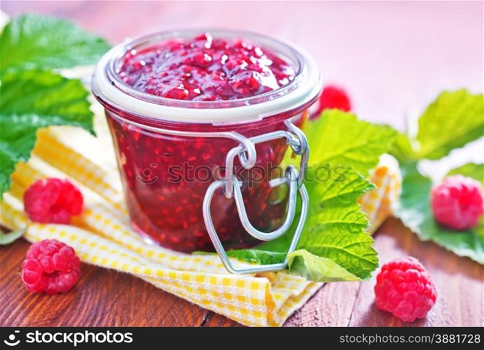 raspberry jam in glass bank and on a table