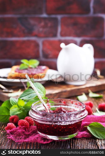 raspberry jam in glass bank and on a table