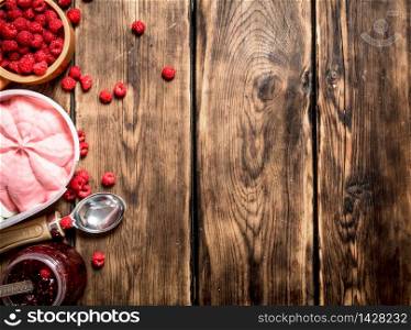 Raspberry jam with ice cream and wild berries. On a wooden table.. Raspberry jam with ice cream and wild berries.
