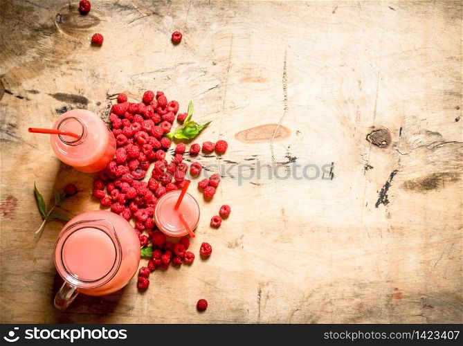 Raspberry juice in the pitcher and glasses. On a wooden table.. Raspberry juice in the pitcher and glasses.