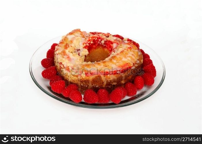 Raspberry Ring Cake. Raspberry ring cake and fresh raspberries on a clear glass plate on a white background
