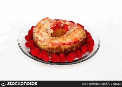 Raspberry Ring Cake. Raspberry ring cake and fresh raspberries on a clear glass plate on a white background