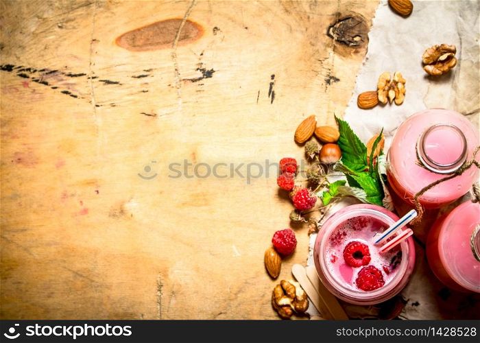Raspberry smoothie with berries, mint and nuts. On wooden background.. Raspberry smoothie with berries, mint and nuts.