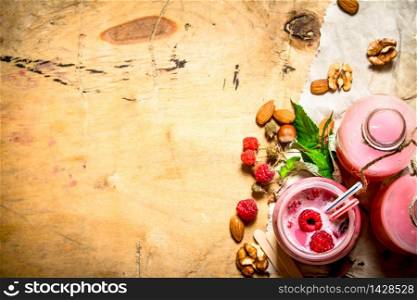 Raspberry smoothie with berries, mint and nuts. On wooden background.. Raspberry smoothie with berries, mint and nuts.