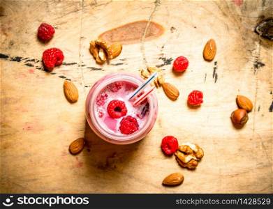 Raspberry smoothie with nuts. On wooden background.. Raspberry smoothie with nuts.