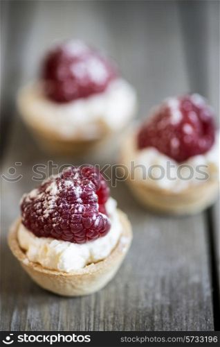 Raspberry tartlets on rustic wooden background