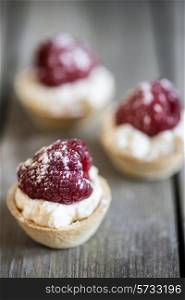 Raspberry tartlets on rustic wooden background