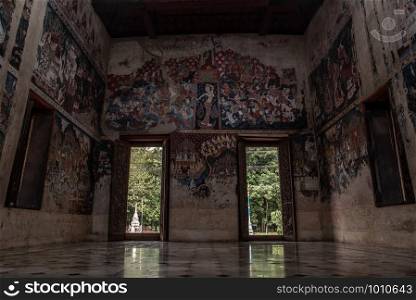 Ratchaburi, Thailand - Sep 22,2019 : Within the church of Wat Kongkharam Rajavaravihara Temple (Photharam), Open old wooden door in temple and church wall tell the story of Buddhism.