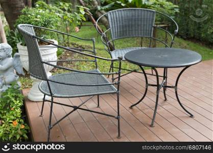 rattan wicker chair and desk on patio beside garden in rainy day