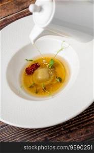 Ravioli consomme on a white porcelain plate. Healthy eating concept