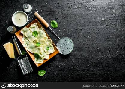 Ravioli with sour cream, spices and Parmesan. On black rustic background. Ravioli with sour cream, spices and Parmesan.