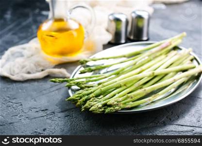 raw asparagus on metal plate and on a table