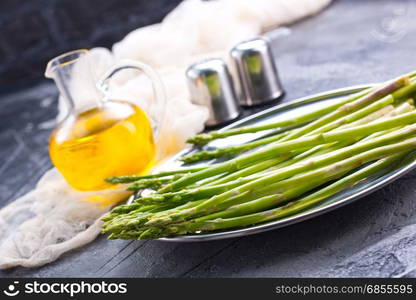 raw asparagus on metal plate and on a table