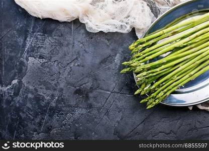 raw asparagus on metal plate and on a table