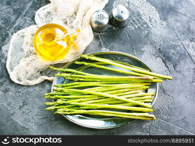 raw asparagus on metal plate and on a table