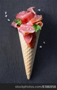 Raw Bacon in ice cream cone on black stone table