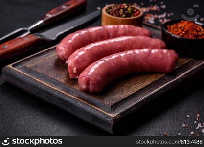 Raw barbecue sausages with spices and vegetables. Free space for your text. Raw sausages with ingredients on a cutting board on a stone background with copy space
