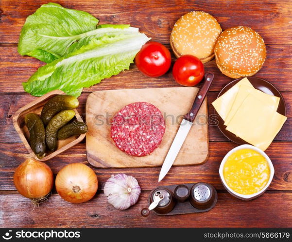 Raw beef burger for hamburger with vegetables on wooden table