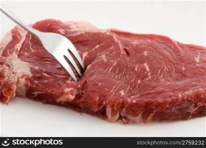 Raw beef. Close up photo of a fork in a raw beef
