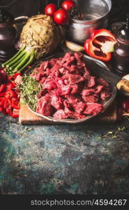 Raw Beef goulash of young bulls with vegetables and cooking ingredients on dark rustic background , preparation, border