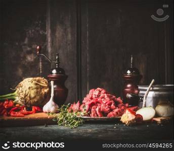 Raw Beef goulash with vegetables and cooking ingredients on dark rustic kitchen table , preparation.